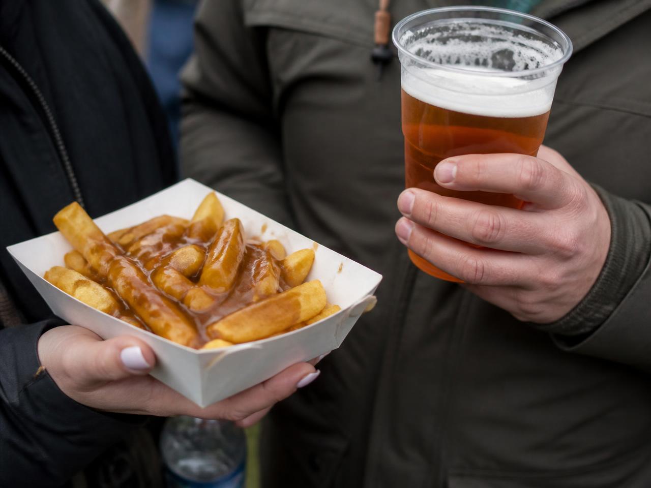 Spectators with chips and a pint in the stand at an outdoor event